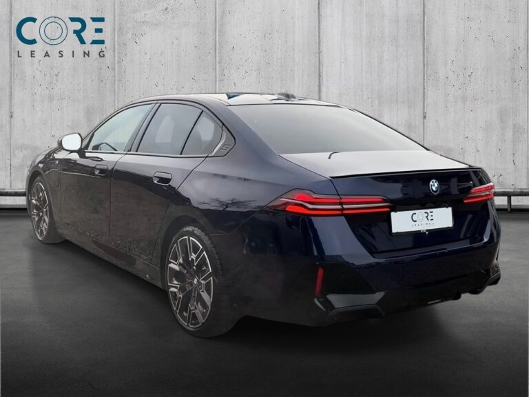 Blåmetal BMW 550e M-Sport xDrive aut. fra 2024 parkeret foran en betonmur. CORE Leasing A/S er eksperter i BMW leasing.