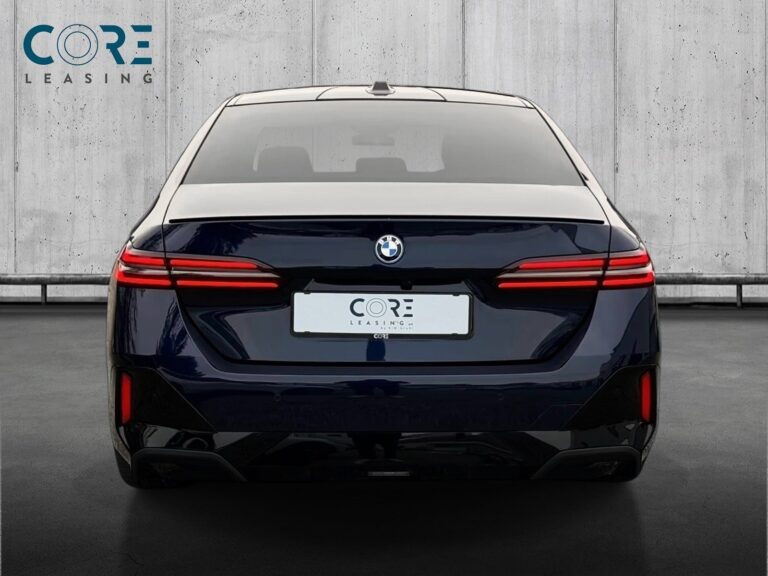 Blåmetal BMW 550e M-Sport xDrive aut. fra 2024 parkeret foran en betonmur. CORE Leasing A/S er eksperter i BMW leasing.