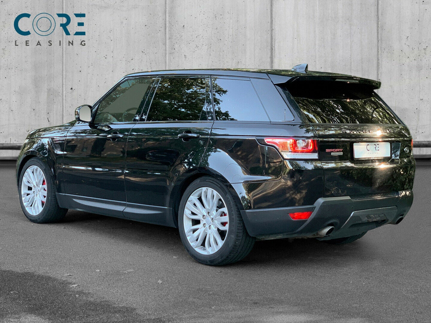 Sortmetal Land Rover Range Rover Sport SCV8 HSE Dynamic aut. fra 2017 parkeret foran en betonmur. CORE Leasing A/S er eksperter i Land Rover leasing.