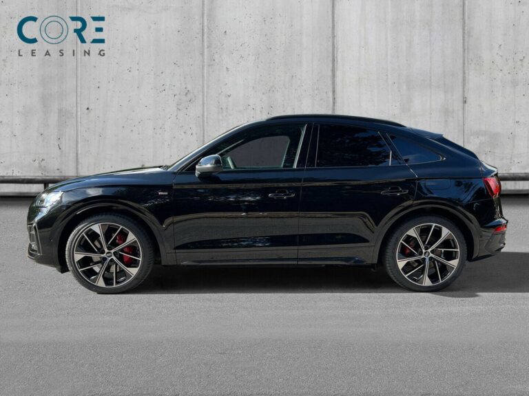 Sortmetal Audi Q5 TFSi e S-line Sportback quattro S-tr. fra 2021 parkeret foran en betonmur. CORE Leasing A/S er eksperter i Audi leasing.