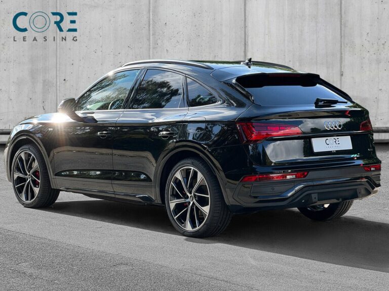 Sortmetal Audi Q5 TFSi e S-line Sportback quattro S-tr. fra 2021 parkeret foran en betonmur. CORE Leasing A/S er eksperter i Audi leasing.
