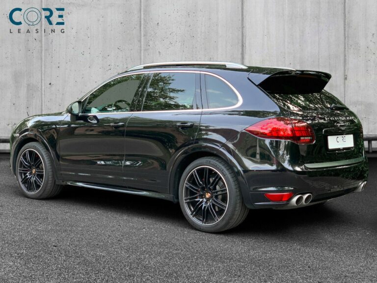 Sortmetal Porsche Cayenne GTS Tiptr. fra 2013 parkeret foran en betonmur. CORE Leasing A/S er eksperter i Porsche leasing.