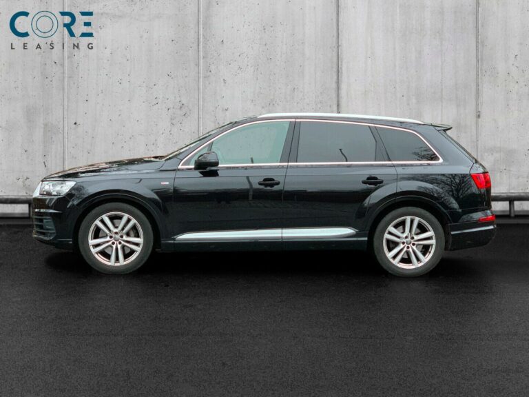 Sortmetal Audi Q7 TDi 272 S-line quattro Tiptr. 7prs fra 2015 parkeret foran en betonmur. CORE Leasing A/S er eksperter i Audi leasing.