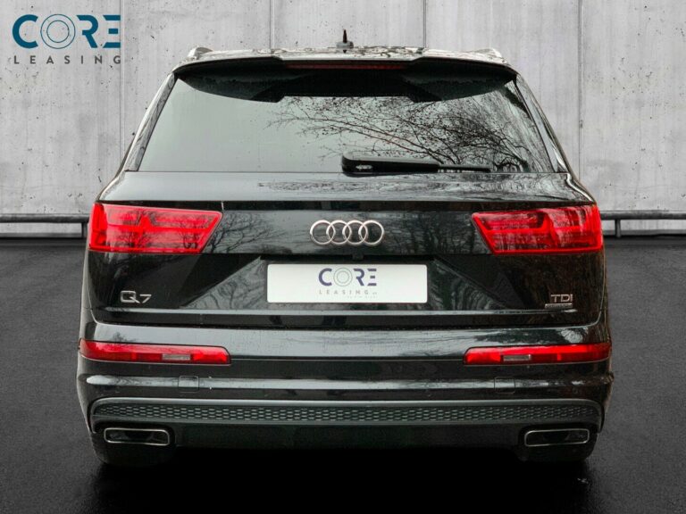 Sortmetal Audi Q7 TDi 272 S-line quattro Tiptr. 7prs fra 2015 parkeret foran en betonmur. CORE Leasing A/S er eksperter i Audi leasing.