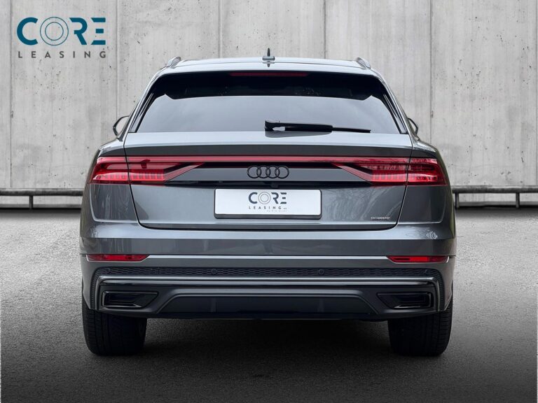 Gråmetal Audi Q8 TDi S-line quattro Tiptr. fra 2019 parkeret foran en betonmur. CORE Leasing A/S er eksperter i Audi leasing.