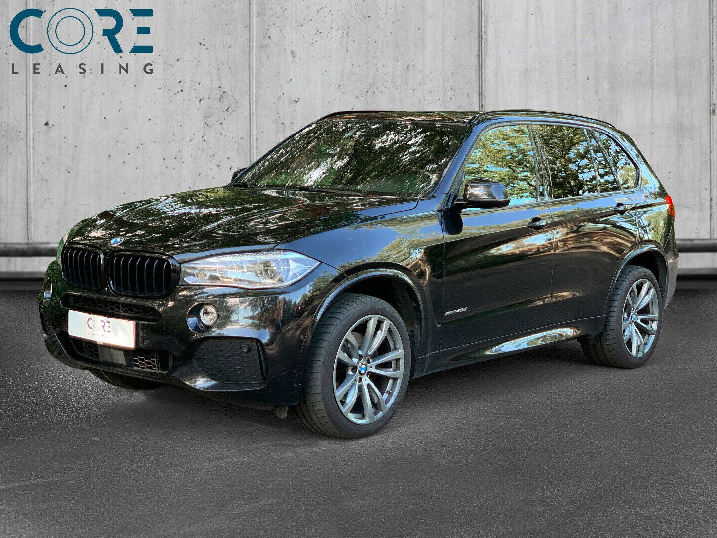 Sortmetal BMW X5 xDrive40d M-Sport aut. 7prs fra 2016 parkeret foran en betonmur. CORE Leasing A/S er eksperter i BMW leasing.