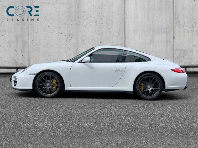 Hvidmetal Porsche 911 Carrera 4 GTS Coupé fra 2012 parkeret foran en betonmur. CORE Leasing A/S er eksperter i Porsche leasing.