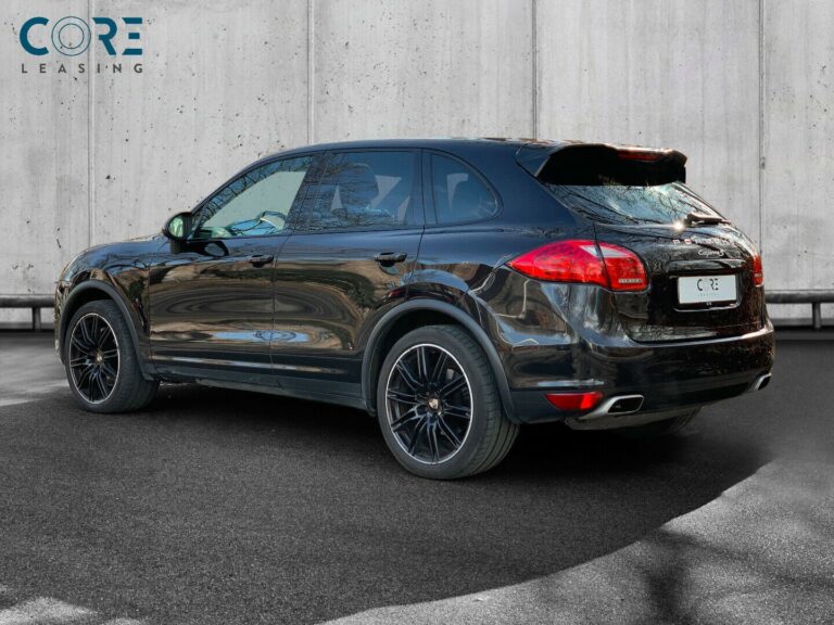 Sortmetal Porsche Cayenne S Tiptr. fra 2011 parkeret foran en betonmur. CORE Leasing A/S er eksperter i Porsche leasing.