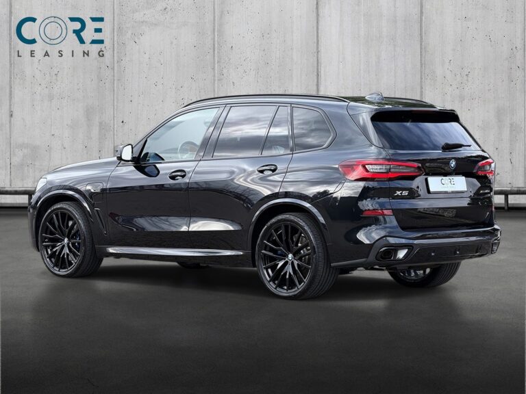 Sortmetal BMW X5 xDrive45e M-Sport aut. fra 2023 parkeret foran en betonmur. CORE Leasing A/S er eksperter i BMW leasing.