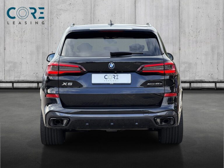 Sortmetal BMW X5 xDrive45e M-Sport aut. fra 2023 parkeret foran en betonmur. CORE Leasing A/S er eksperter i BMW leasing.