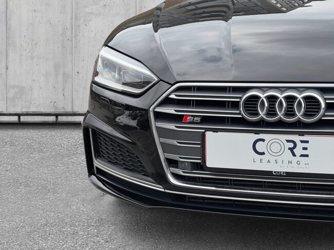Sortmetal Audi S5 TFSi Cabriolet quattro Tiptr. fra 2017 parkeret foran en betonmur. CORE Leasing A/S er eksperter i Audi leasing.
