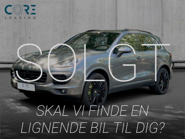 Gråmetal Porsche Cayenne S E-Hybrid Tiptr. fra 2016 parkeret foran en betonmur. CORE Leasing A/S er eksperter i Porsche leasing.