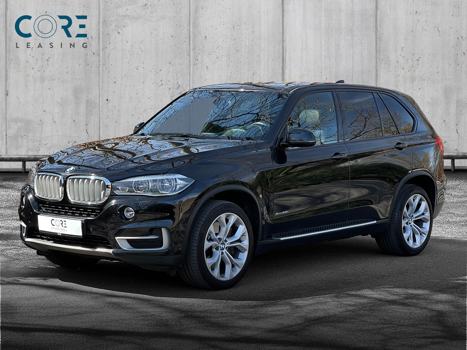 Sortmetal BMW X5 xDrive50i aut. fra 2015 parkeret foran en betonmur. CORE Leasing A/S er eksperter i BMW leasing.