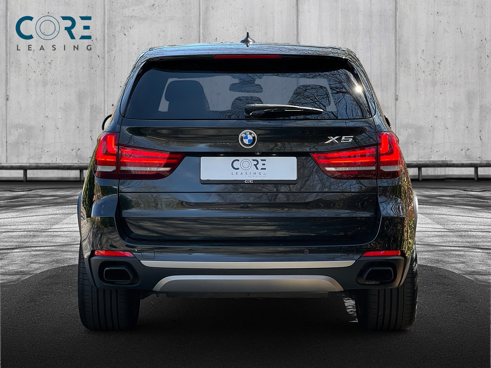 Sortmetal BMW X5 xDrive50i aut. fra 2015 parkeret foran en betonmur. CORE Leasing A/S er eksperter i BMW leasing.
