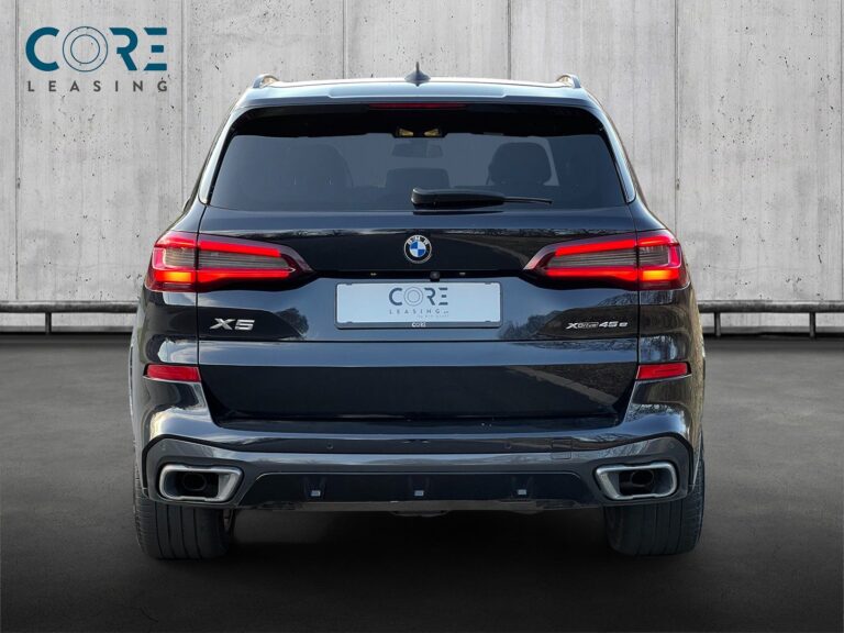 Sortmetal BMW X5 xDrive45e M-Sport aut. fra 2020 parkeret foran en betonmur. CORE Leasing A/S er eksperter i BMW leasing.