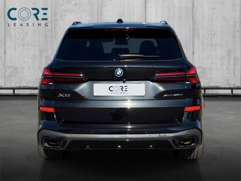 Sortmetal BMW X5 xDrive50e M-Sport+ aut. fra 2024 parkeret foran en betonmur. CORE Leasing A/S er eksperter i BMW leasing.