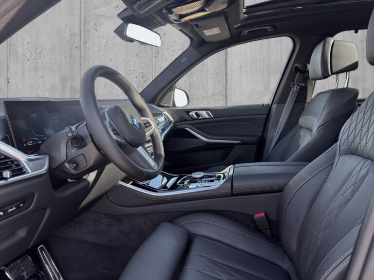 Sortmetal BMW X5 xDrive50e M-Sport+ aut. fra 2024 parkeret foran en betonmur. CORE Leasing A/S er eksperter i BMW leasing.