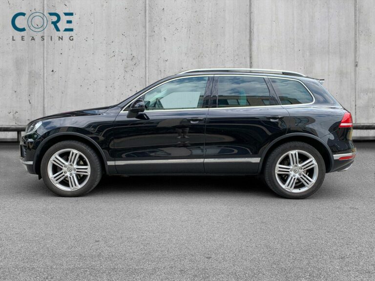 Sortmetal VW Touareg V6 TDi 262 Tiptr. 4Motion fra 2014 parkeret foran en betonmur. CORE Leasing A/S er eksperter i VW leasing.