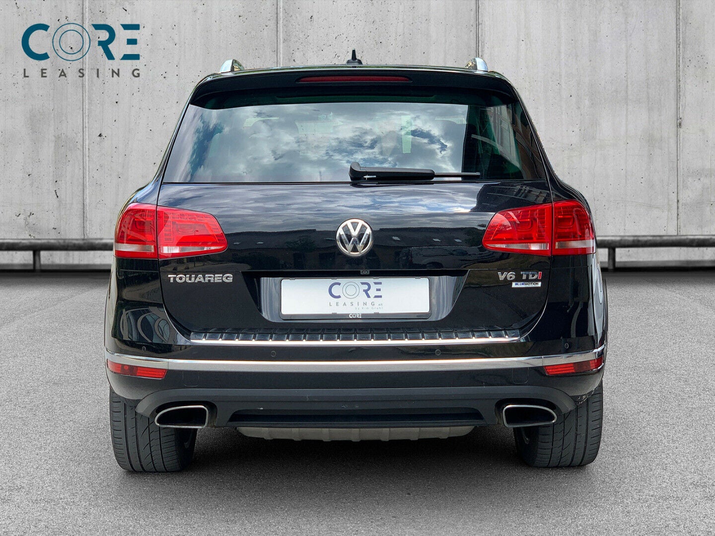 Sortmetal VW Touareg V6 TDi 262 Tiptr. 4Motion fra 2014 parkeret foran en betonmur. CORE Leasing A/S er eksperter i VW leasing.