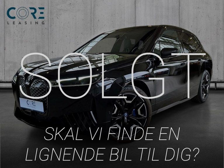 Sortmetal BMW iX xDrive50 Supercharged fra 2024 parkeret foran en betonmur. CORE Leasing A/S er eksperter i BMW leasing.